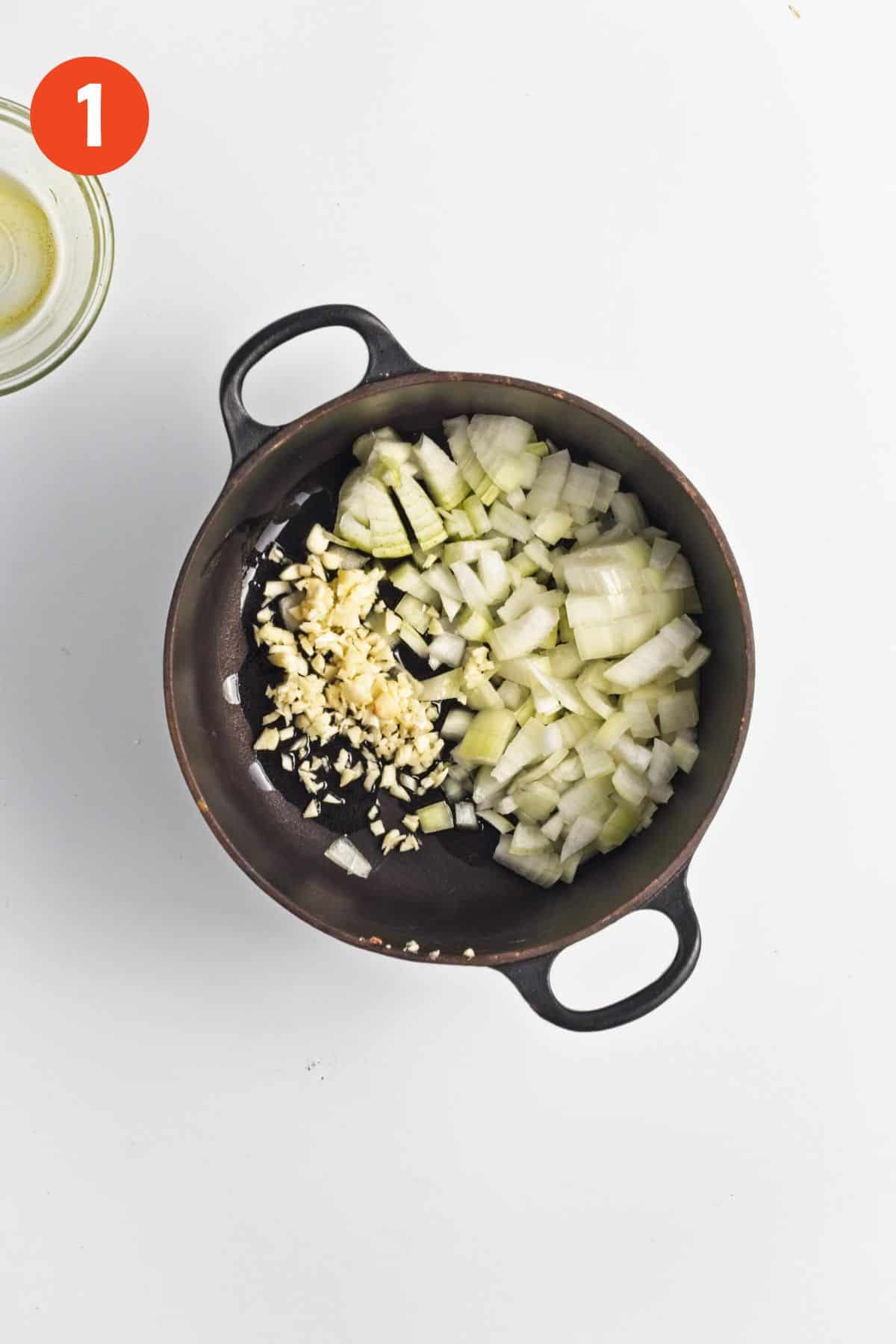 Onions and garlic added to a pot to make carrot soup.