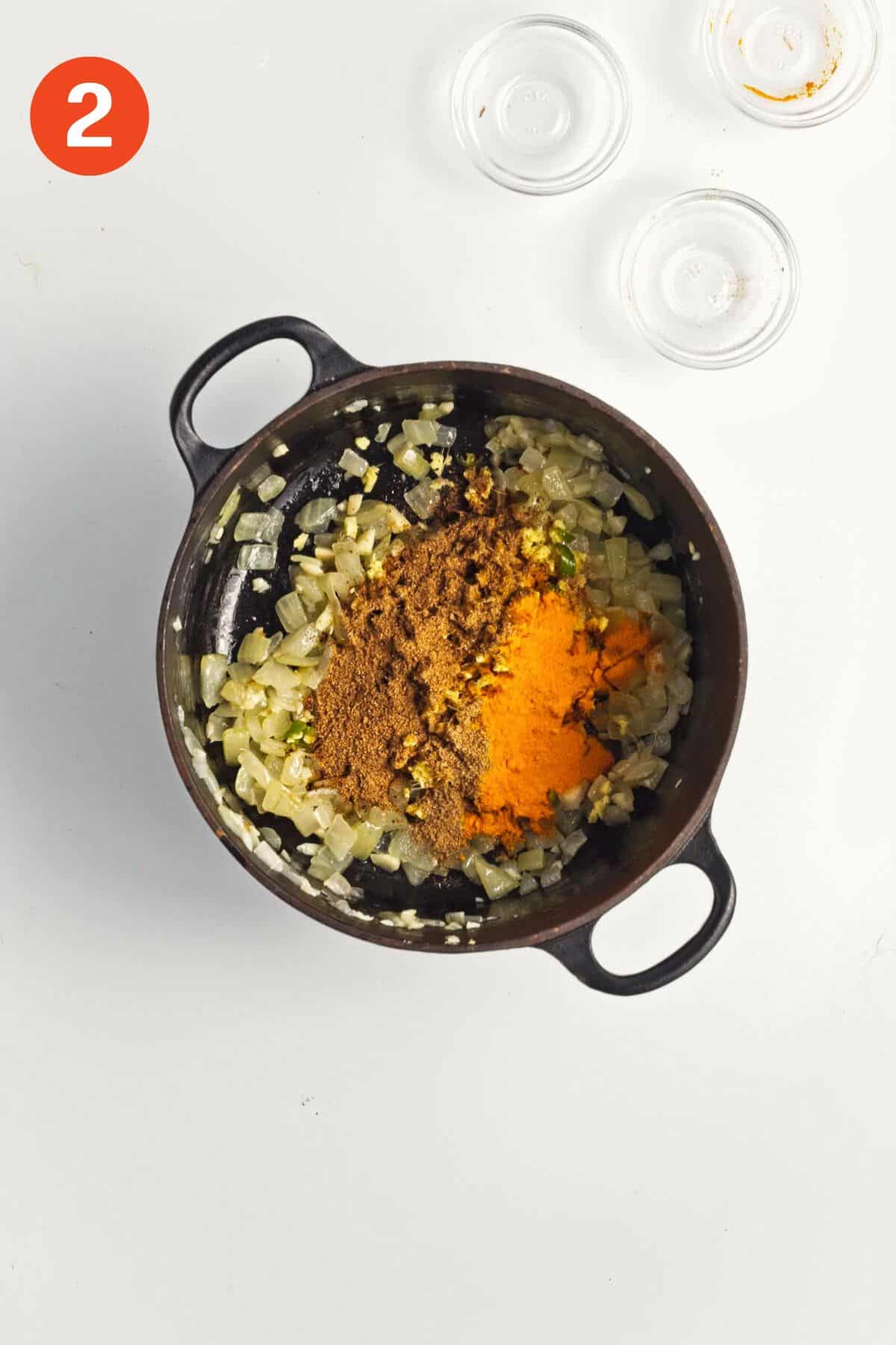 Spices are added to the pot to make carrot ginger soup.