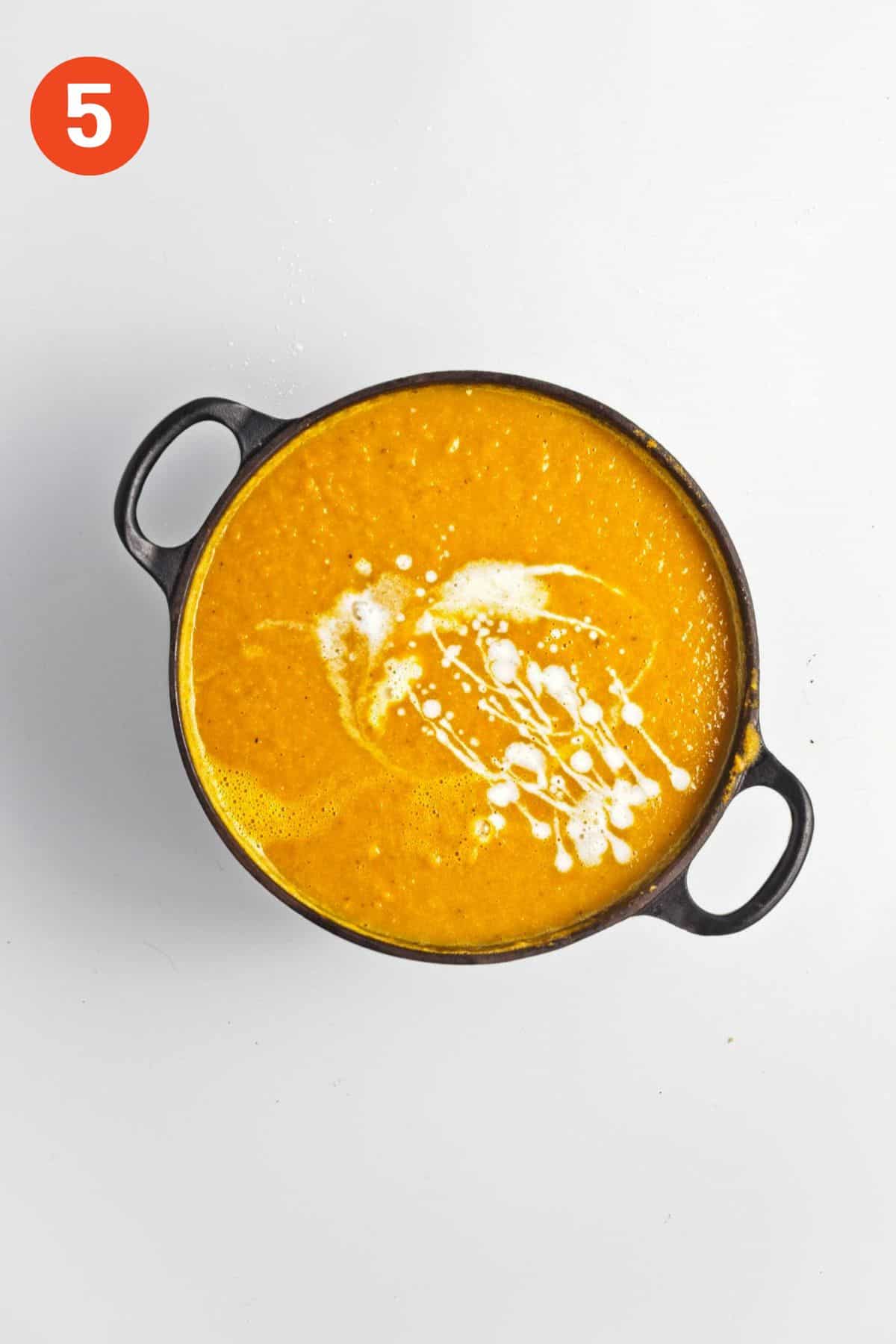 Coconut milk added to blended carrot soup.