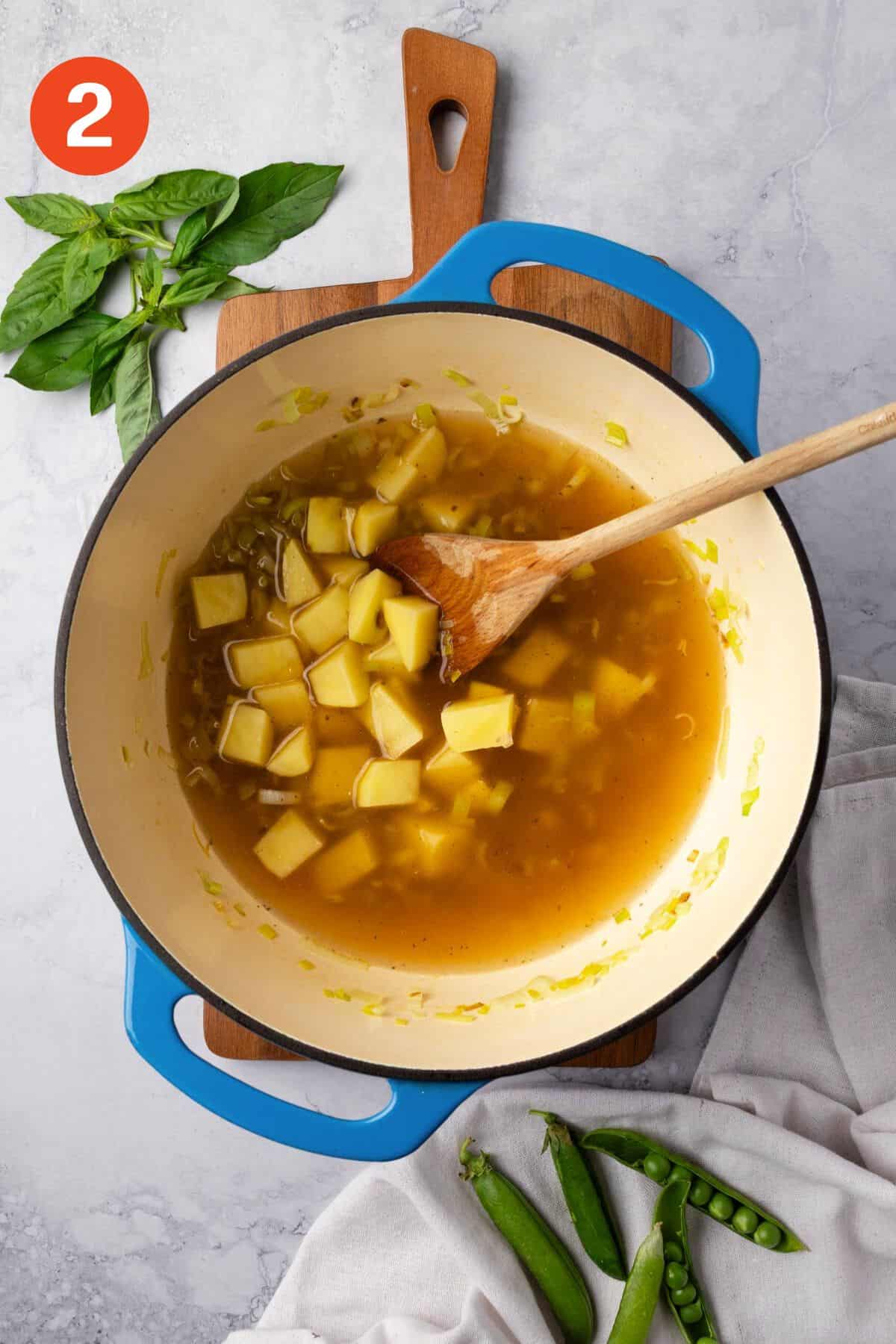 Broth and potatoes added to the leeks in a soup pot.