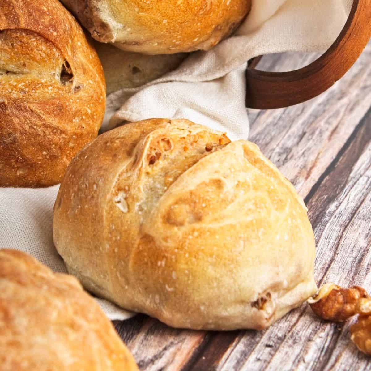 Crusty dinner rolls on a table with a napkin underneath.
