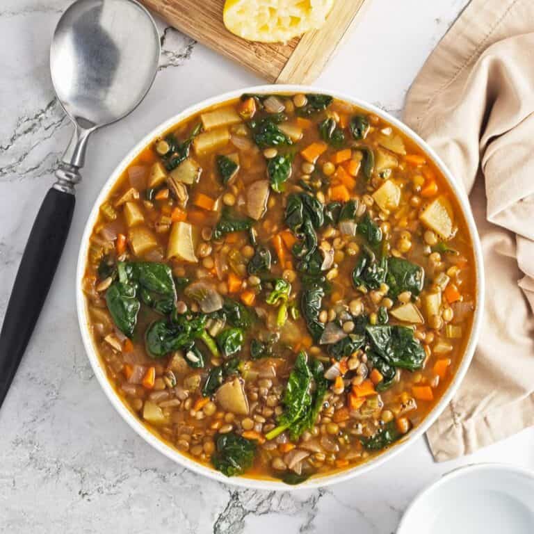 Spinach lentil soup in a white bowl on the table.