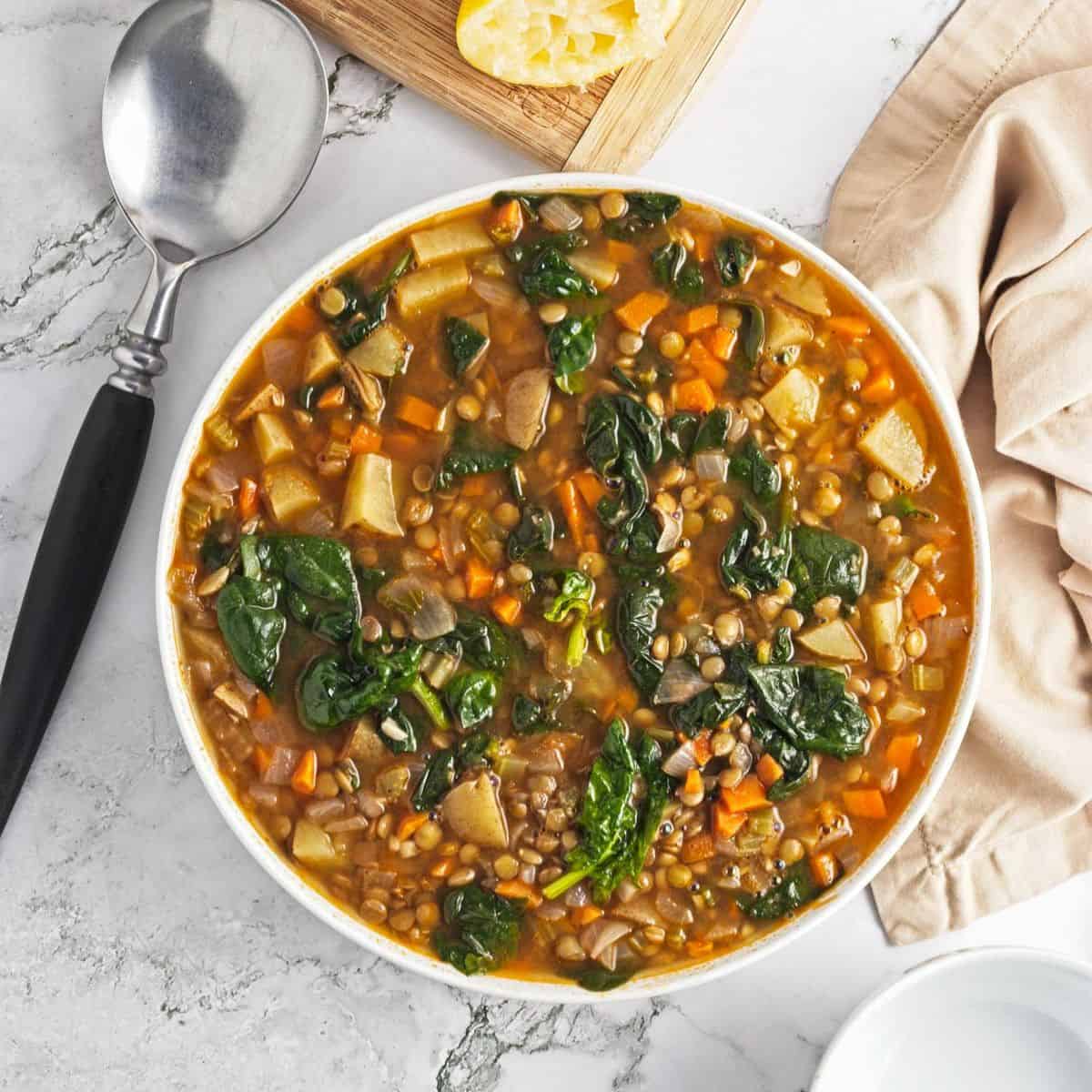 Spinach lentil soup in a white bowl on the table.