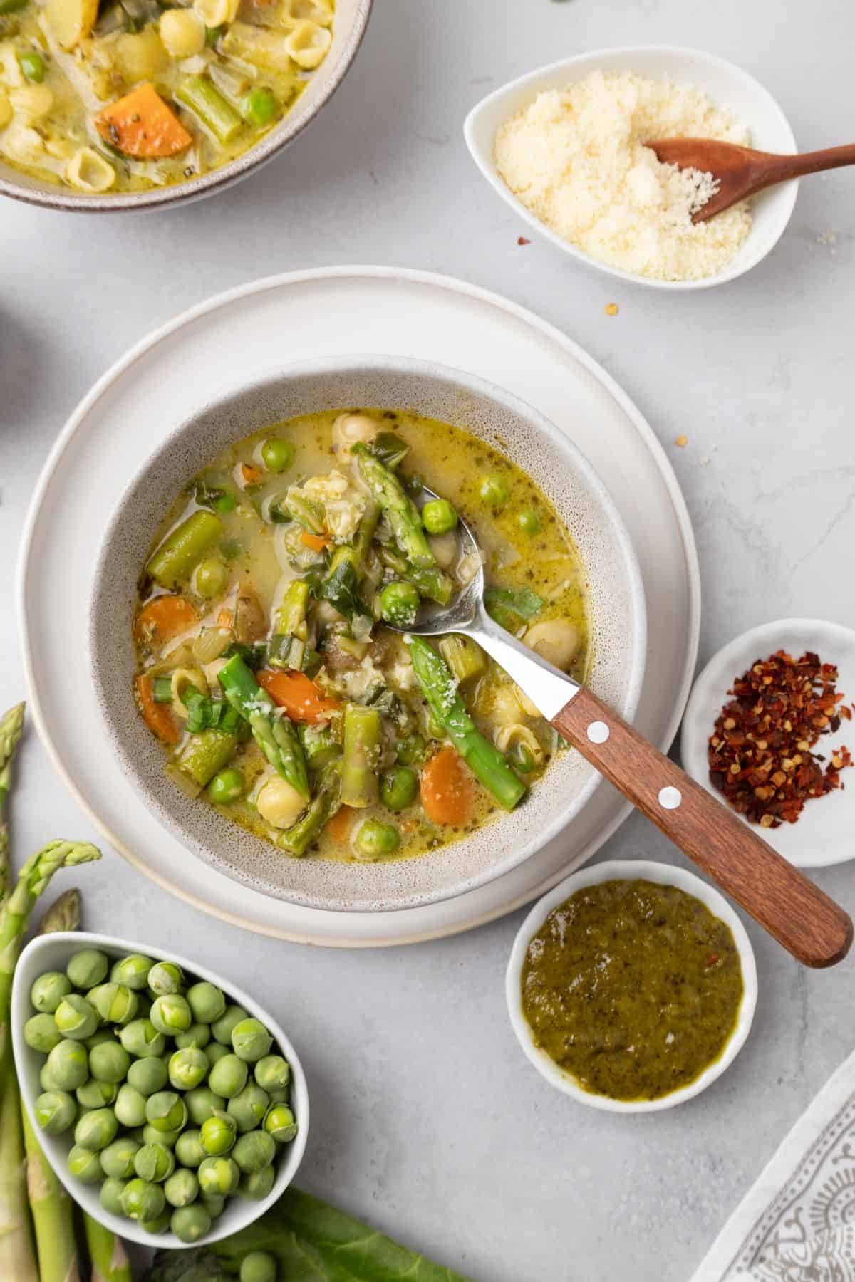 Bowl of spring minestrone soup with a spoon in the bowl.