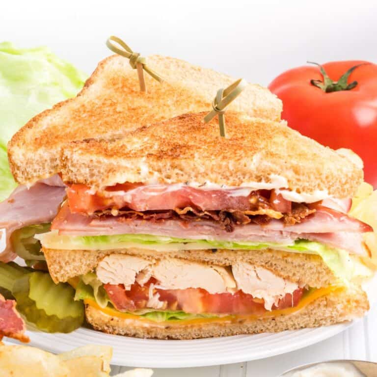 Chicken club sandwich cut in half and stacked on top to show insides.