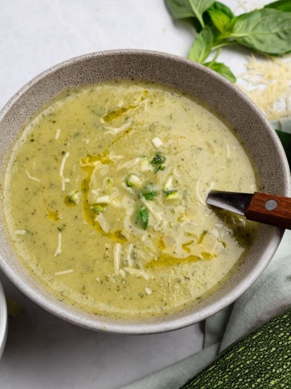 A bowl of basil zucchini soup garnished with some diced zucchini and parmesan cheese.