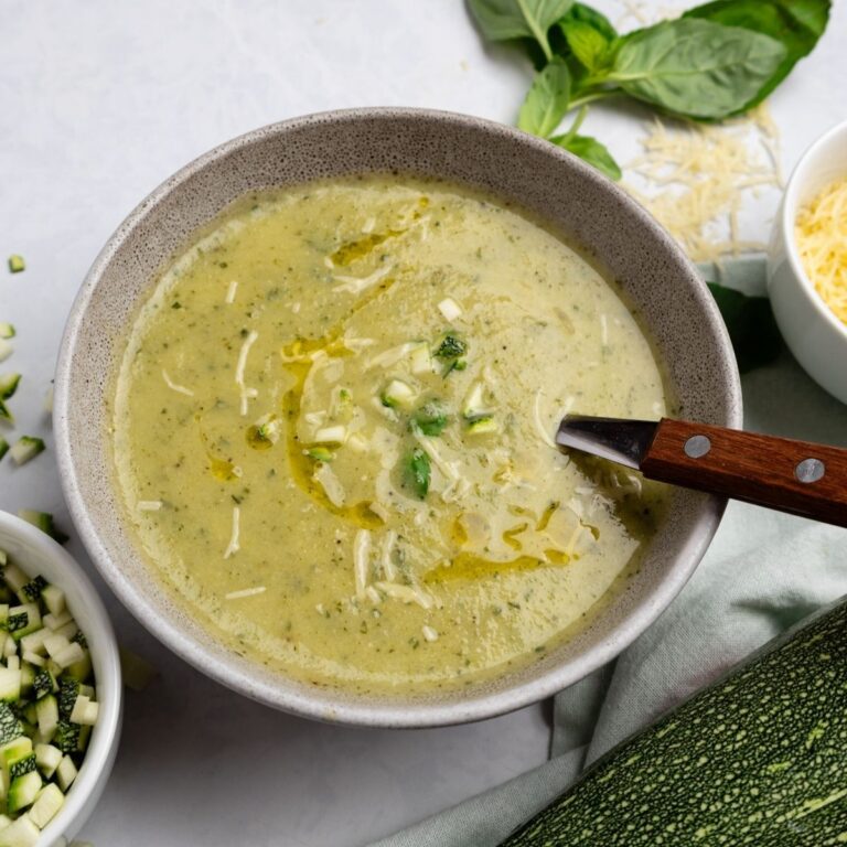 A bowl of basil zucchini soup garnished with some diced zucchini and parmesan cheese.