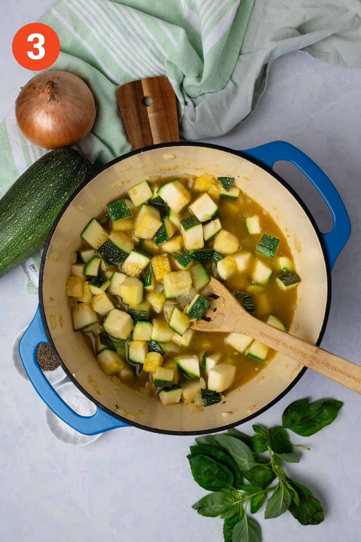 Broth is added to the pot with the zucchini and other vegetables. 