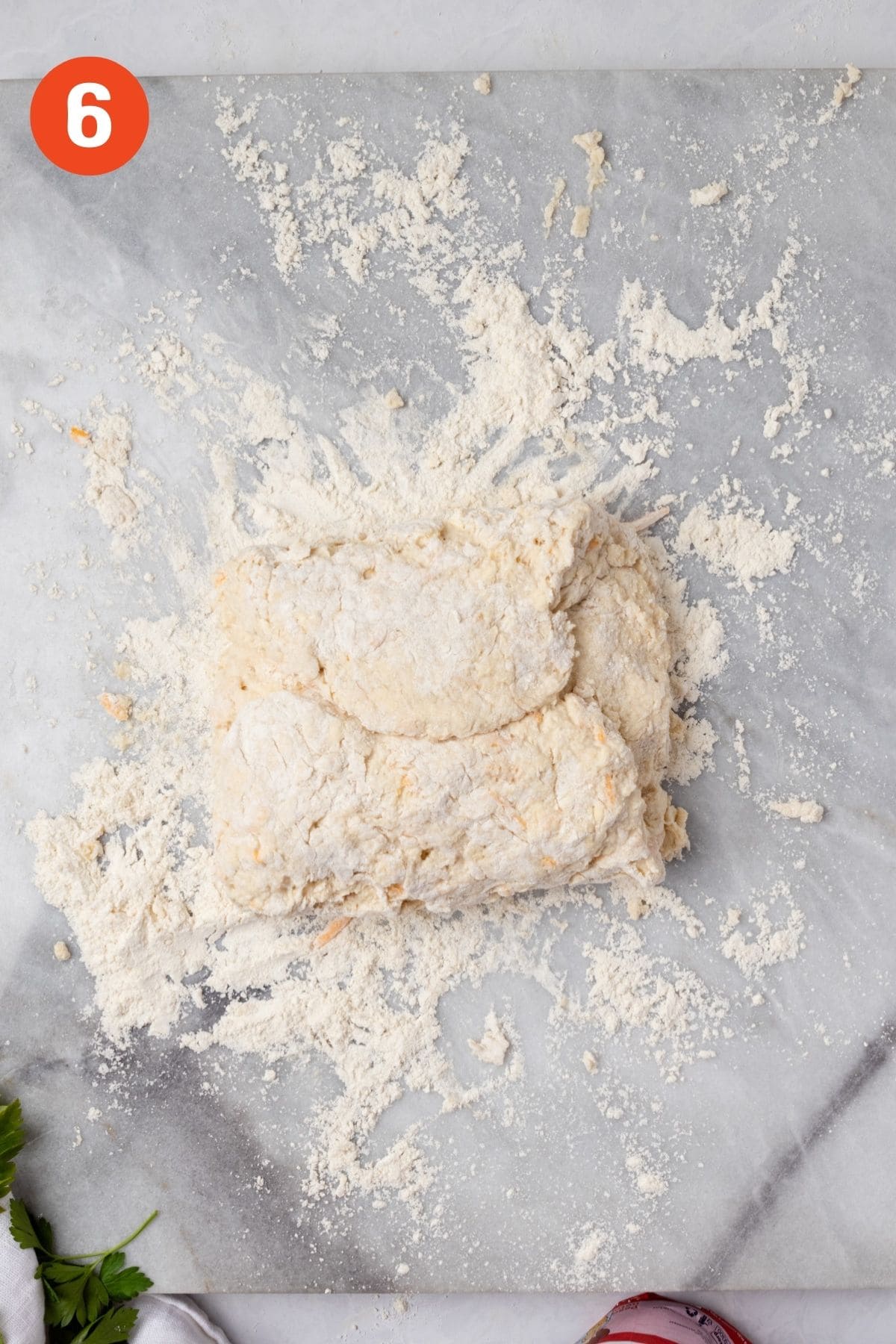 Rectangle of cheddar biscuit dough folded over into thirds.