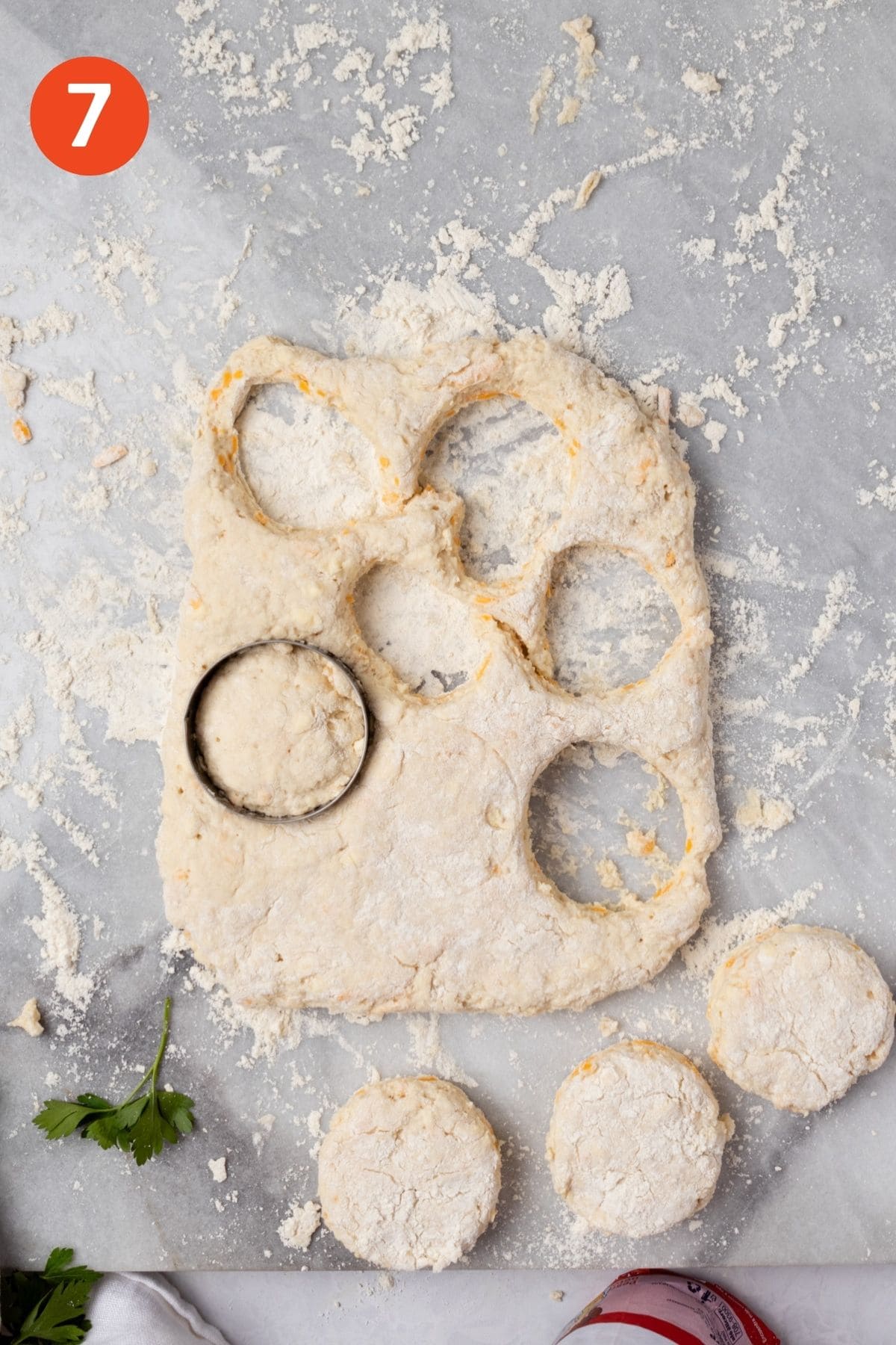 Biscuits cut out of the dough on a marble surface.