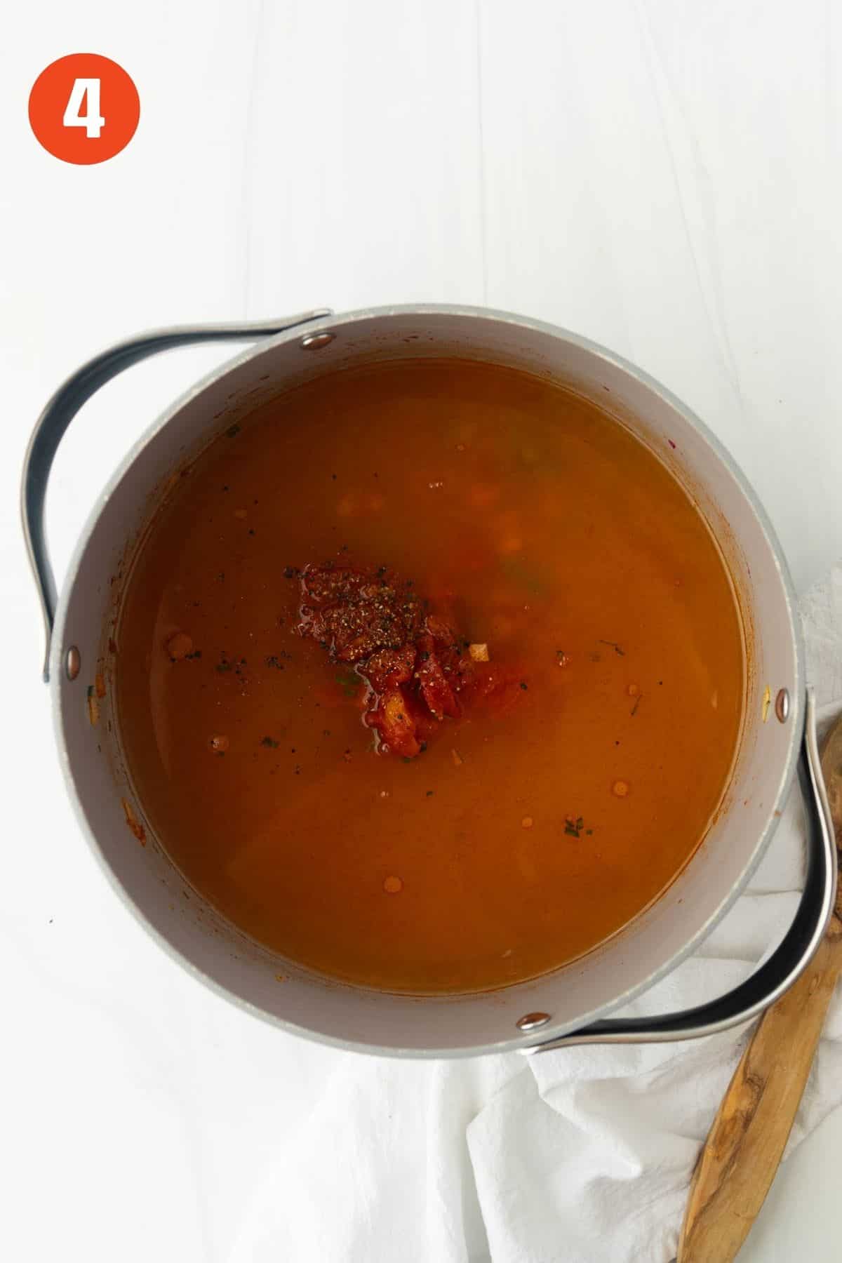 Broth and tomatoes added to the soup pot.