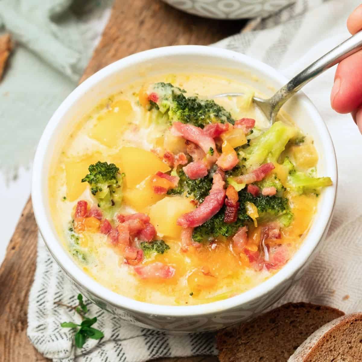 A bowl of potato broccoli cheese soup with a spoon in the bowl.