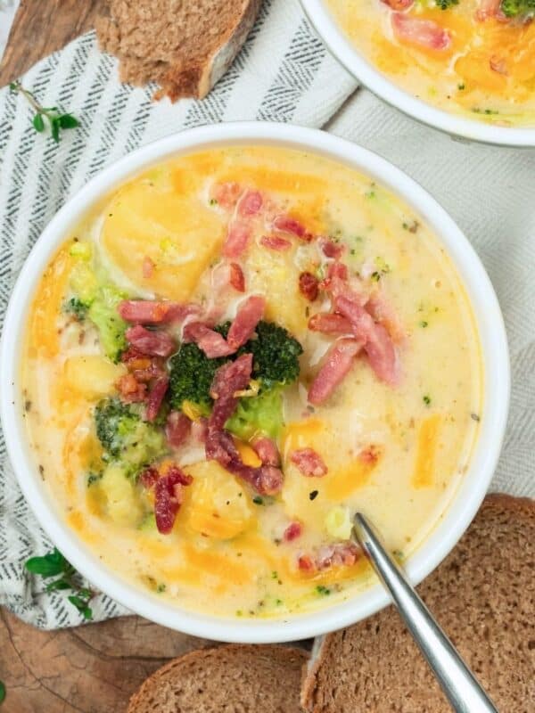 A bowl of potato cheese broccoli soup topped with bacon bits.