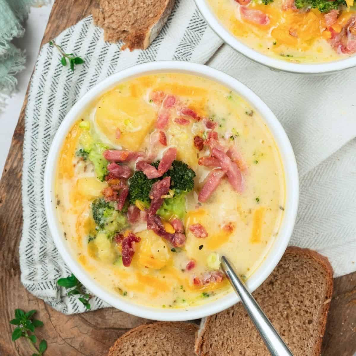 A bowl of potato cheese broccoli soup topped with bacon bits.