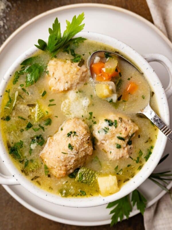 Chicken meatball soup with vegetables and a spoon resting in the soup.