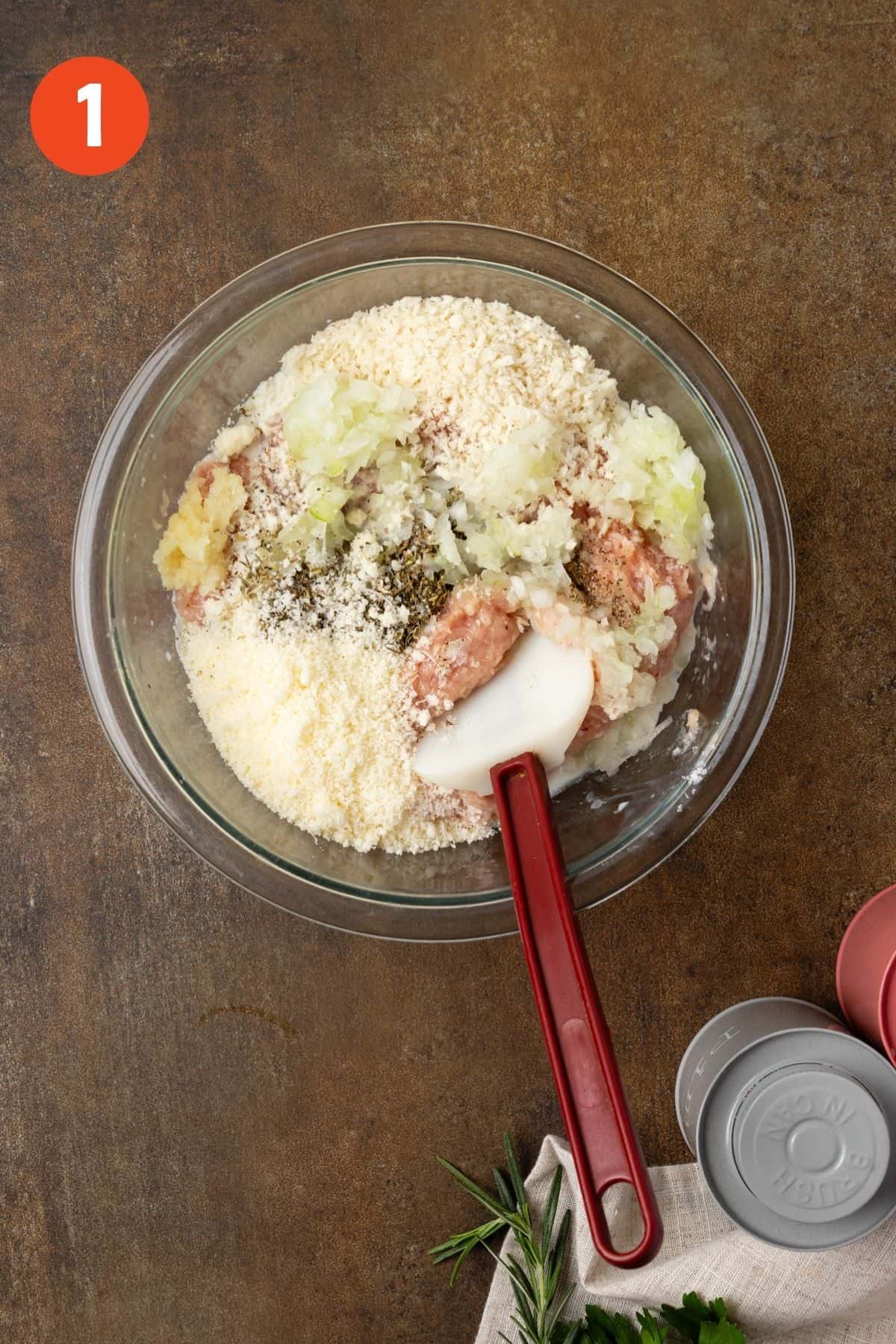 Ingredients for chicken meatballs added to a mixing bowl.