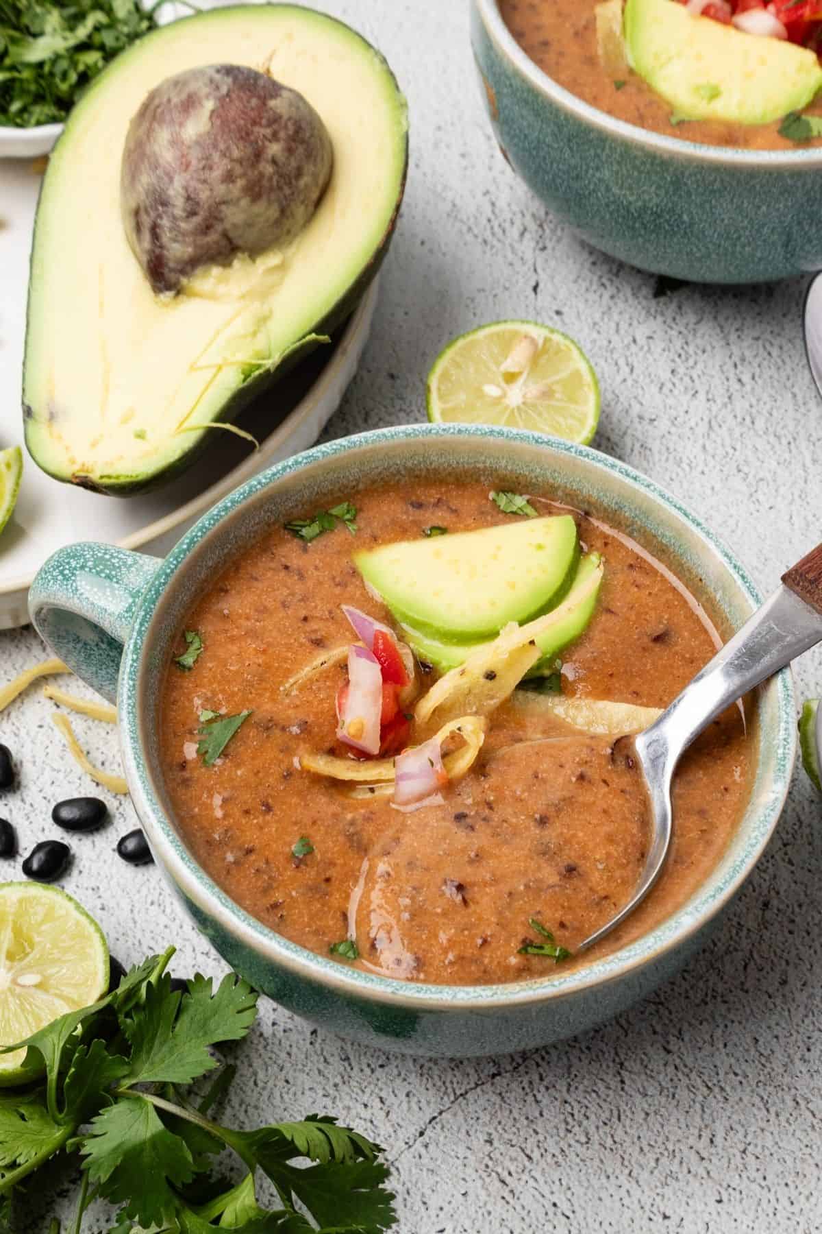 A bowl of black bean soup in the Instant Pot with a spoonful resting in the bowl.