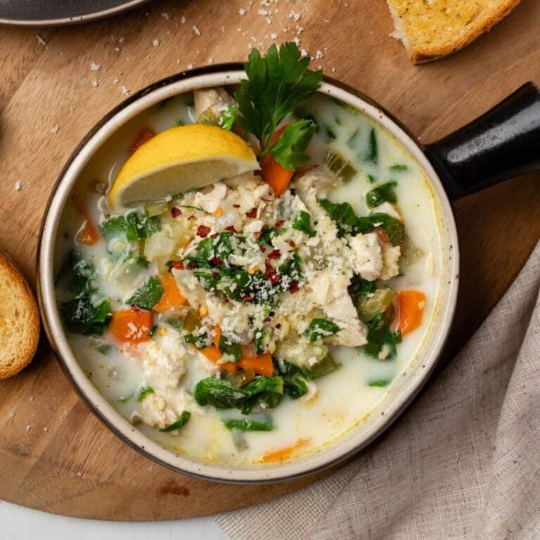 Chicken pastina soup served up in a bowl garnished with lemon wedge and a leaf of parsley.