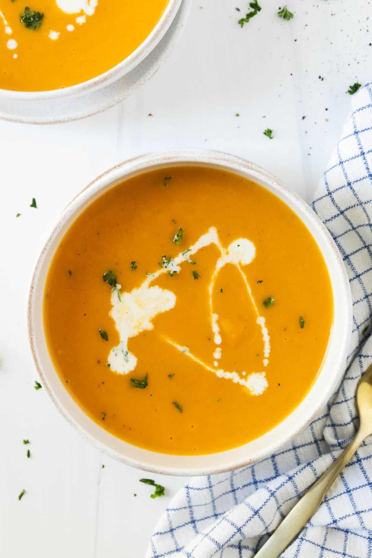 Bowls of Instant Pot butternut squash soup drizzled with cream and sprinkled with parsley.