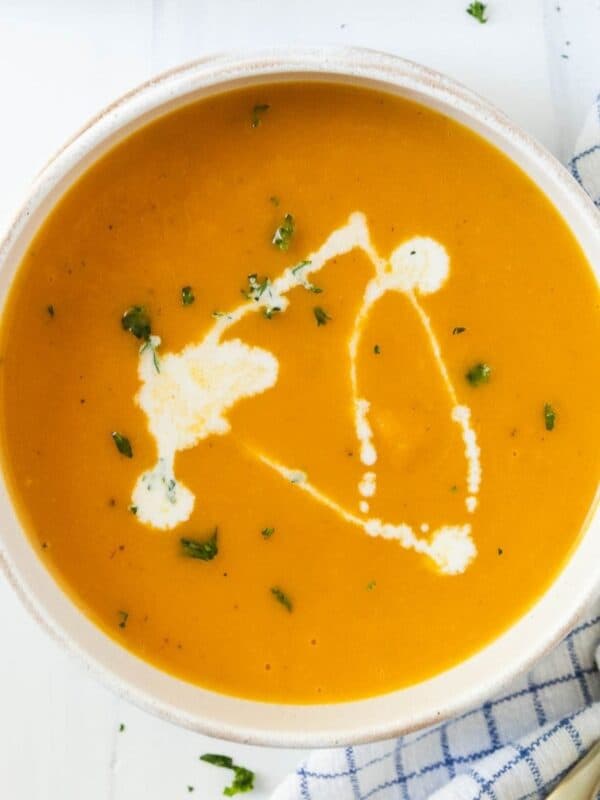 A bowl of Instant Pot butternut squash soup drizzled with half and half and sprinkled with parsley.