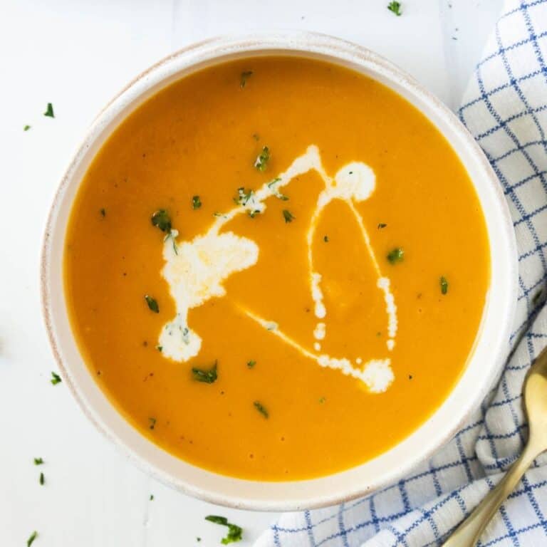 A bowl of Instant Pot butternut squash soup drizzled with half and half and sprinkled with parsley.