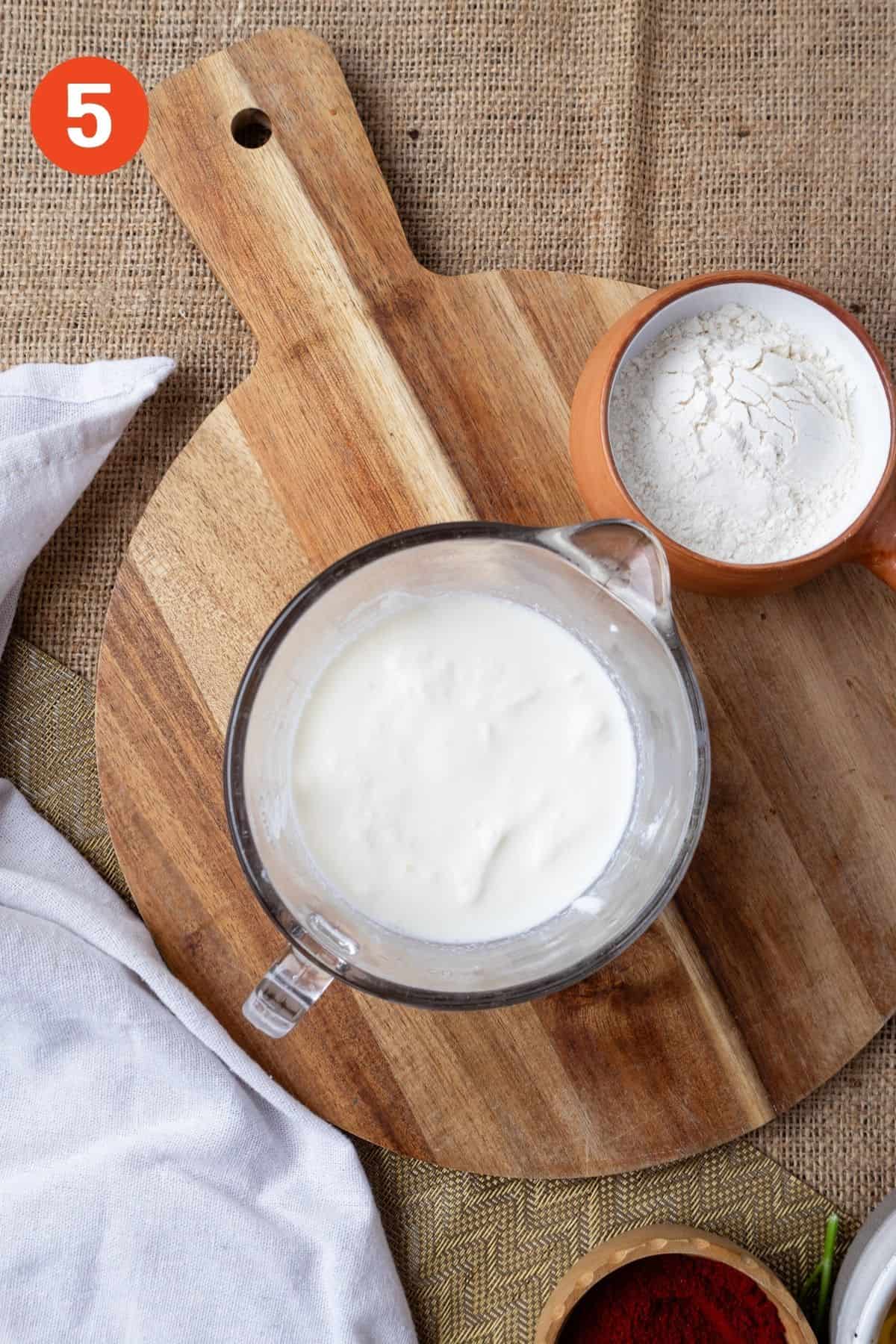 Sour cream, milk, and flour mixed in a measuring cup.
