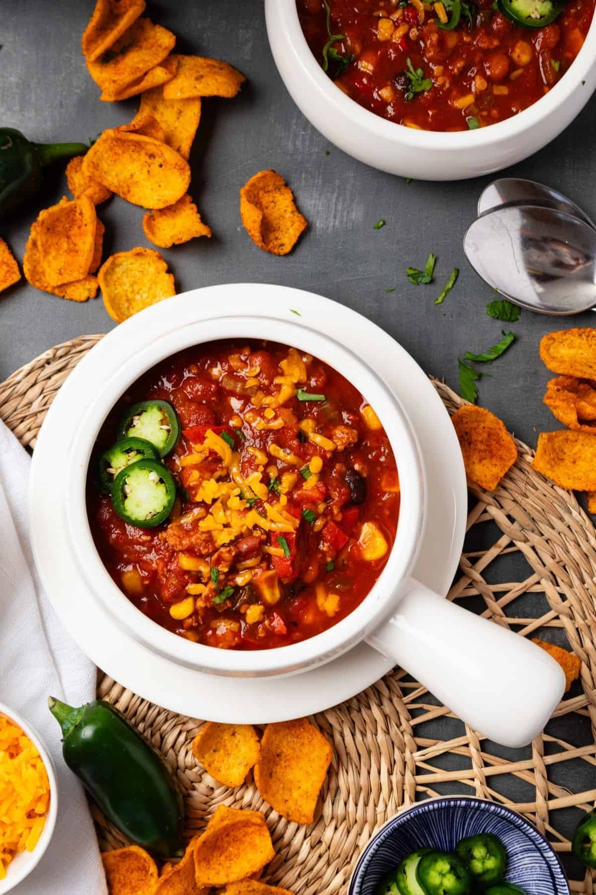 A bowl of turkey chili in the Instant Pot on a table with corn chips scattered around.