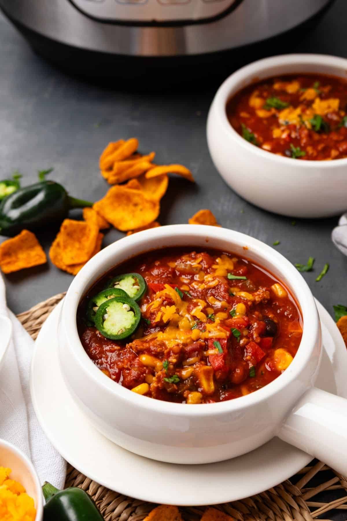 A bowl of turkey chili on a plate with an Instant Pot in the background.