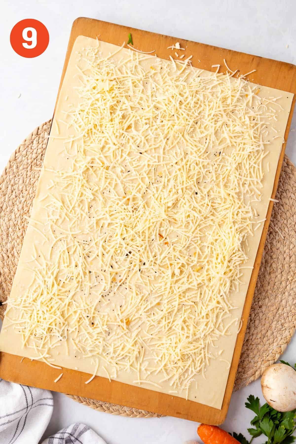 Puff pastry spread out on a cutting board and topped with parmesan cheese.