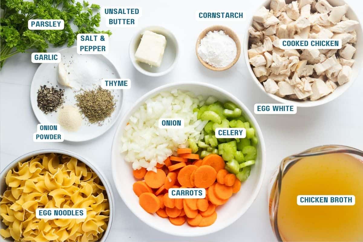 Ingredients to make Panera chicken noodle soup in bowls on a table.