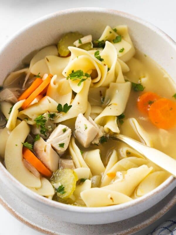 A bowl of copycat Panera Bread chicken noodle soup with a spoon resting in the bowl.