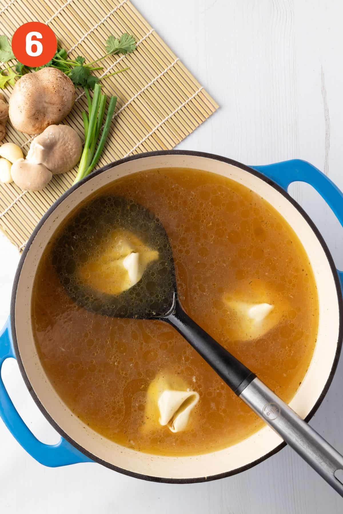 Wontons added to the broth to cook.
