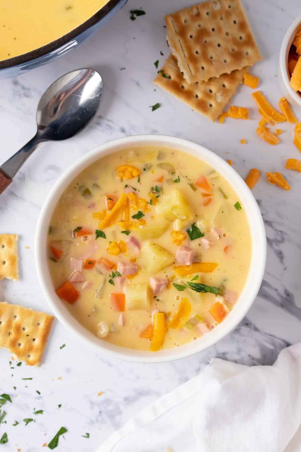 Cheesy ham and potato soup with crackers on the table.