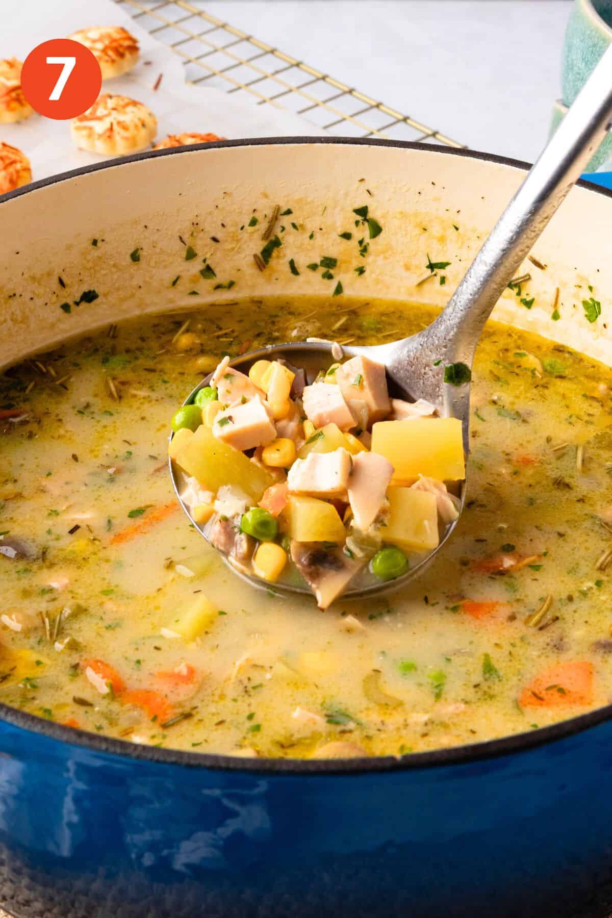 A ladle lifting up a serving of chicken pot pie soup.