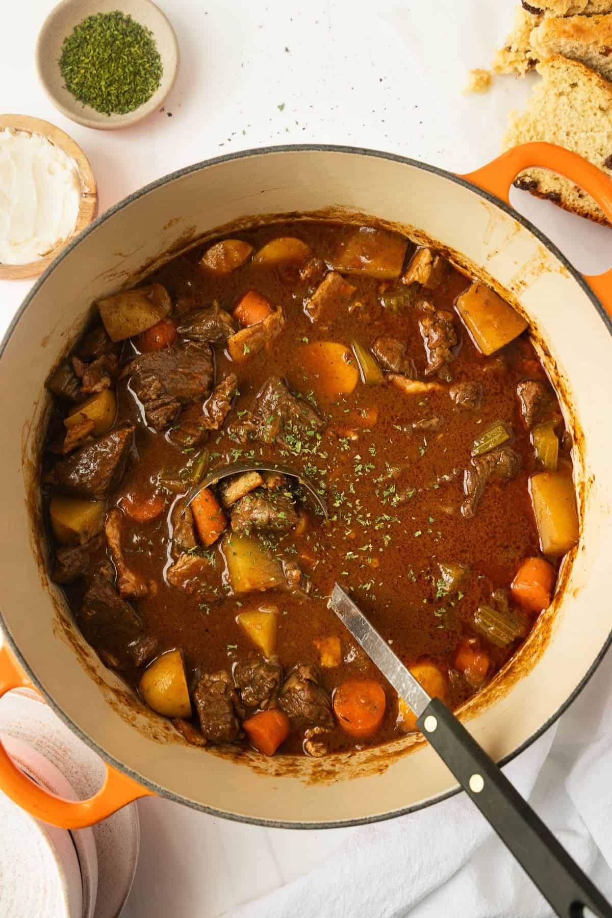 A ladle scooping out some Irish beef stew out of a pot.