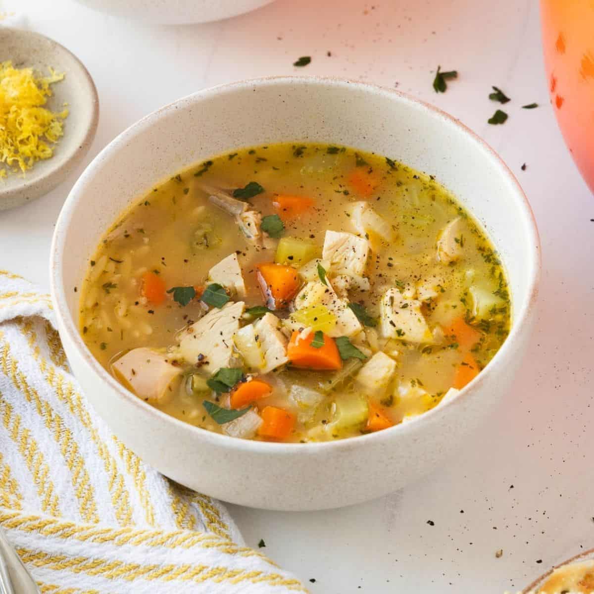 A bowl with chicken orzo soup on a table.