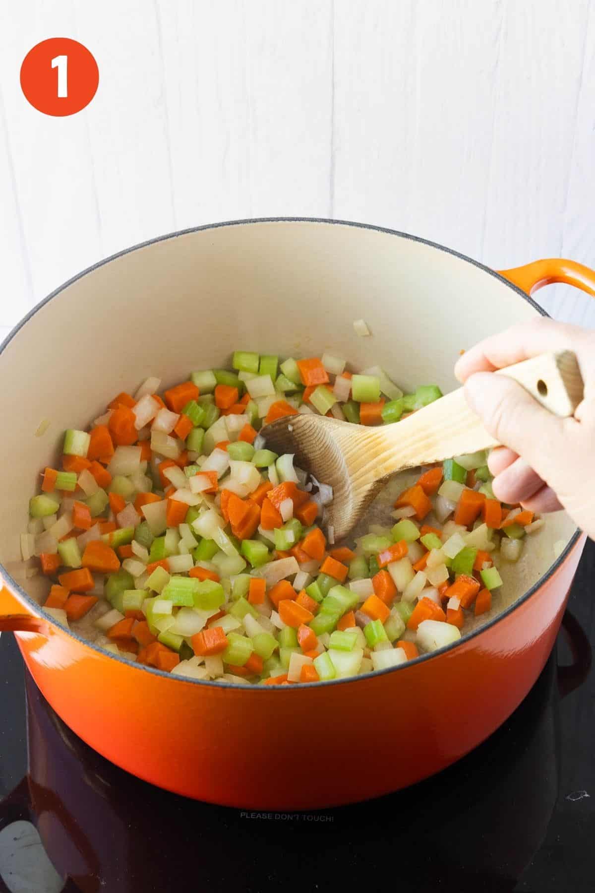 Onions, celery, and carrots being mixed in a pot.