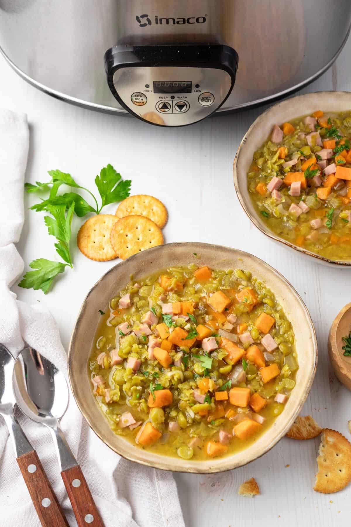 Bowls of split pea soup in front of a slow cooker machine.