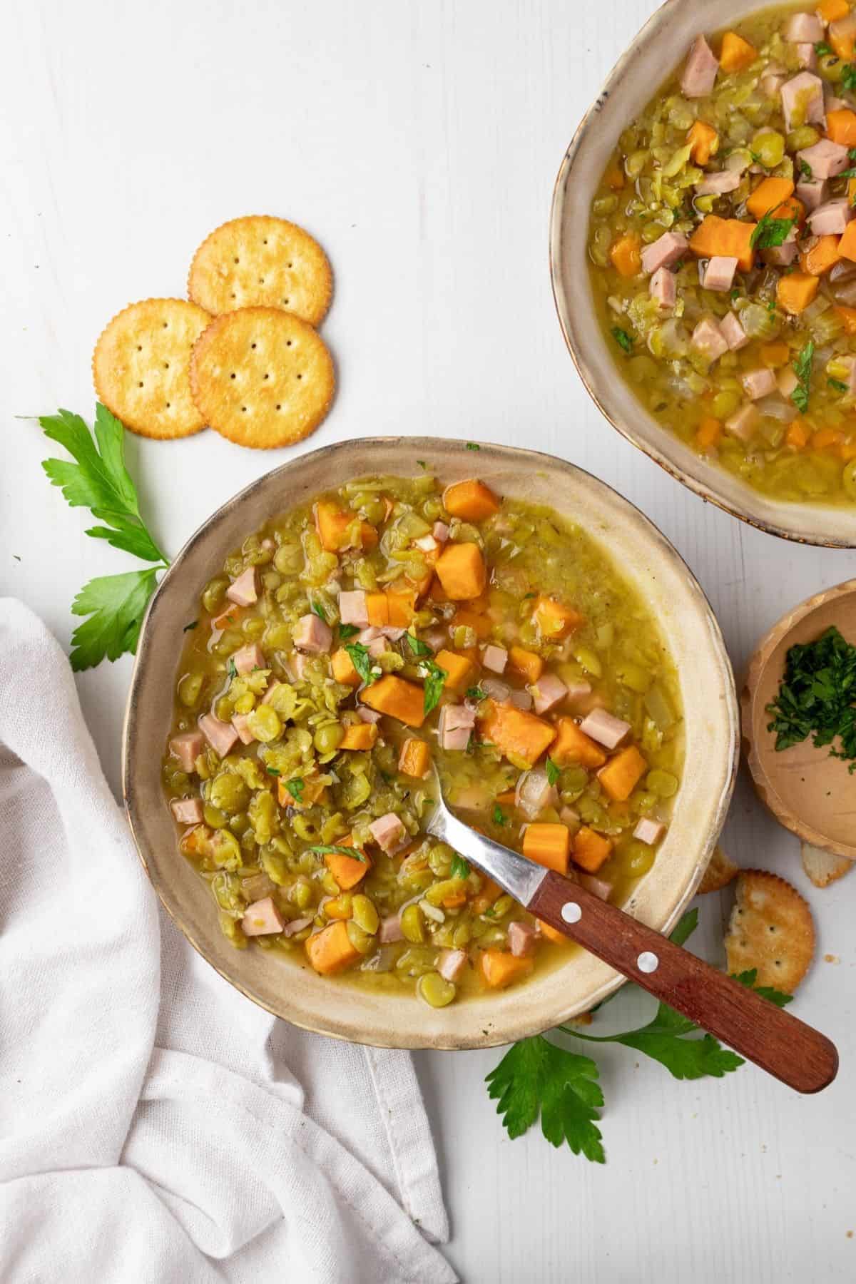A bowl of split pea soup with a spoon in it.
