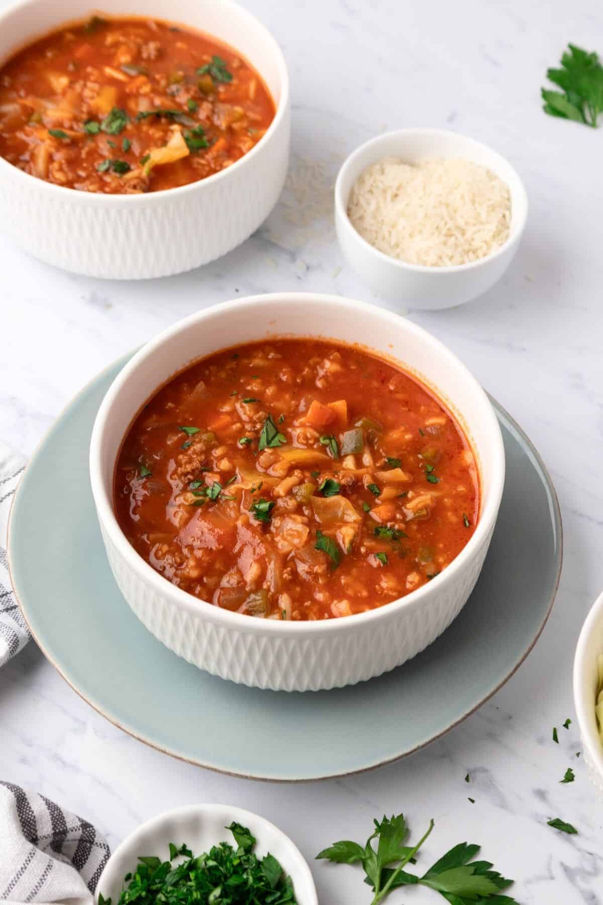 A bowl of unstuffed cabbage soup on a light blue plate.