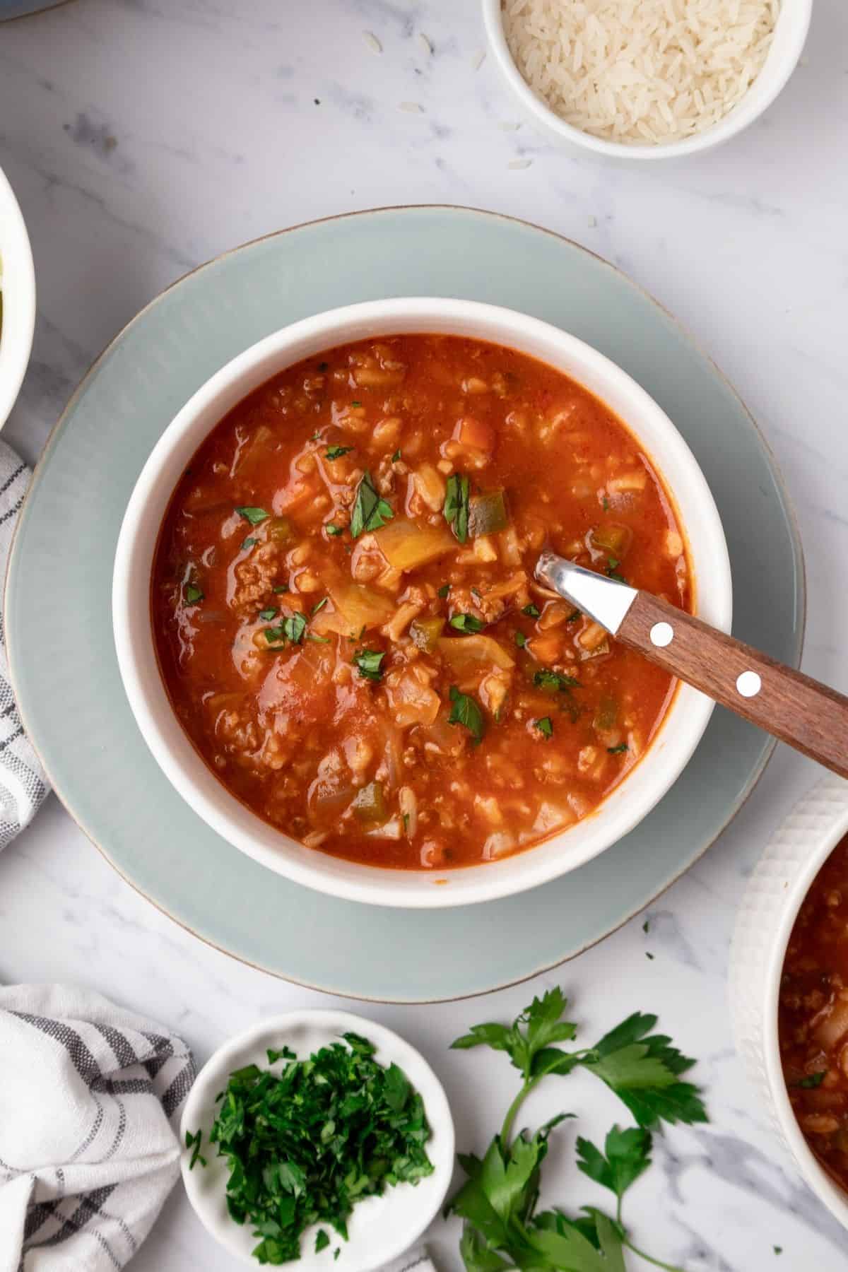 A bowl of unstuffed cabbage soup with a spoon resting in it. 
