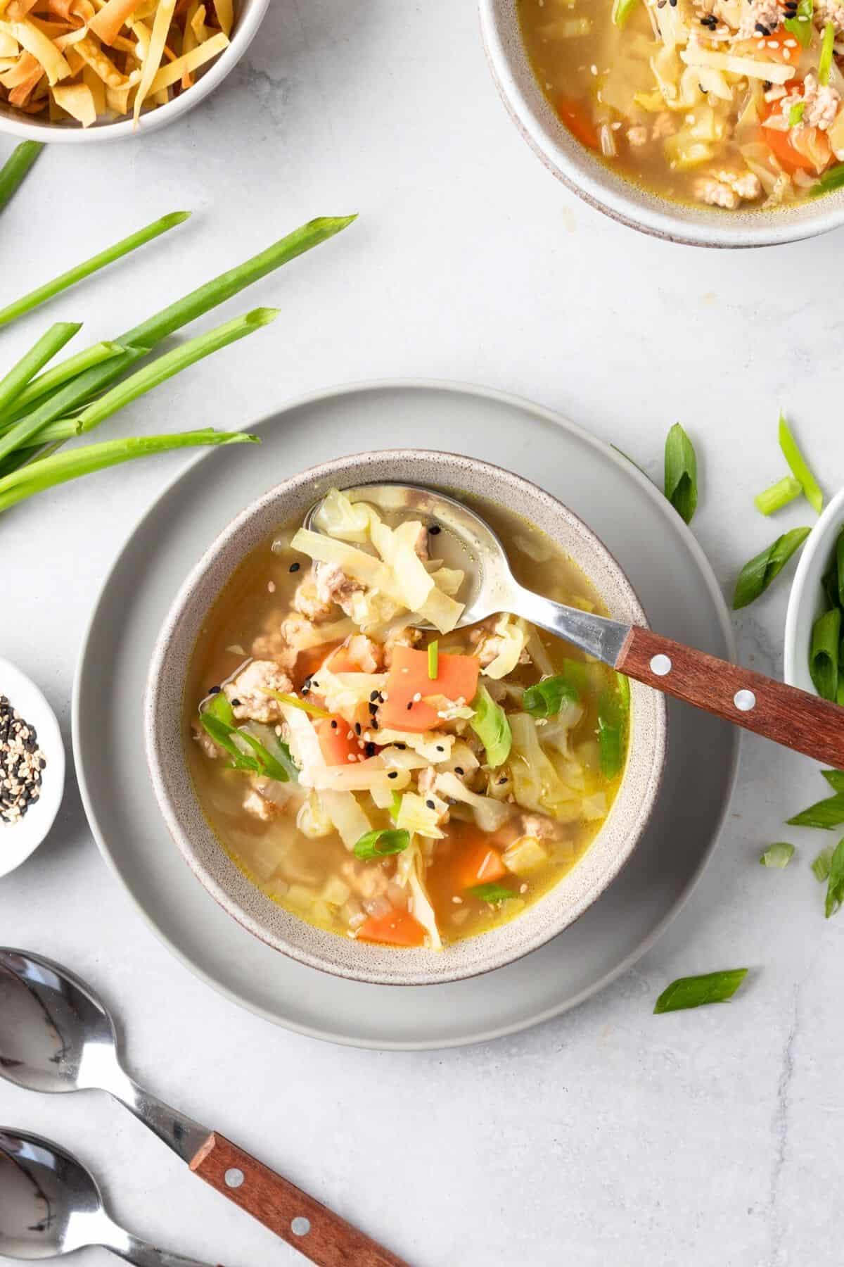 Egg roll soup being taken out with a spoon.