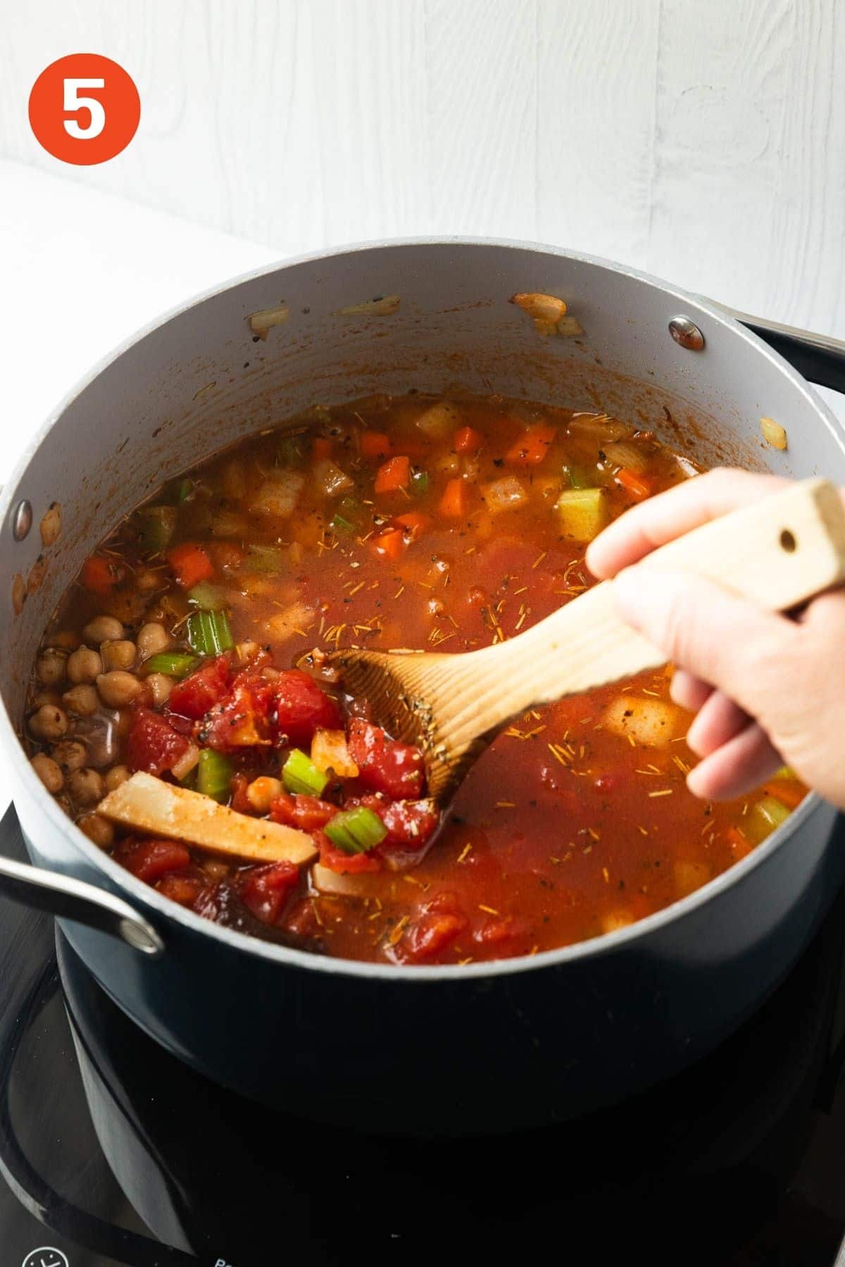 A wooden spoon stirring the soup.