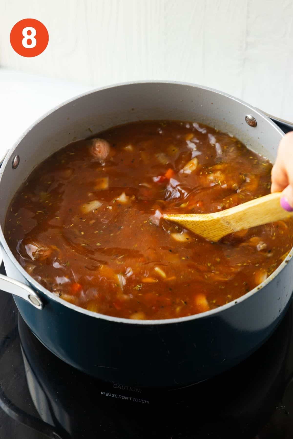Stew being mixed with a wooden spoon.