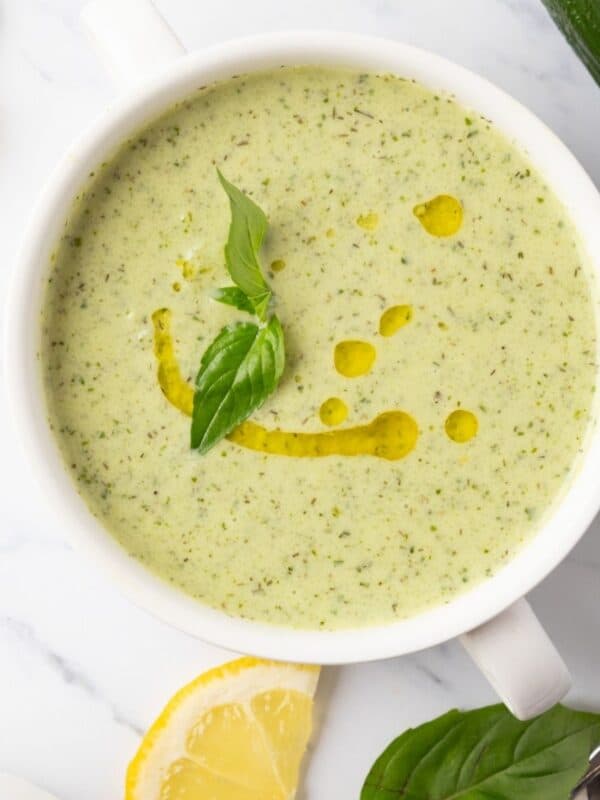 Cucumber soup with oil and a basil leaf on top.