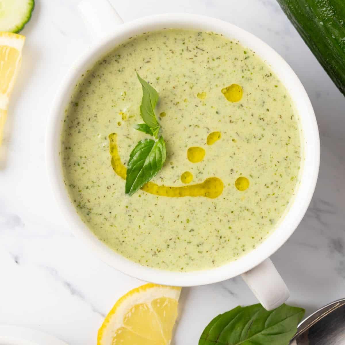 Cucumber soup with oil and a basil leaf on top.