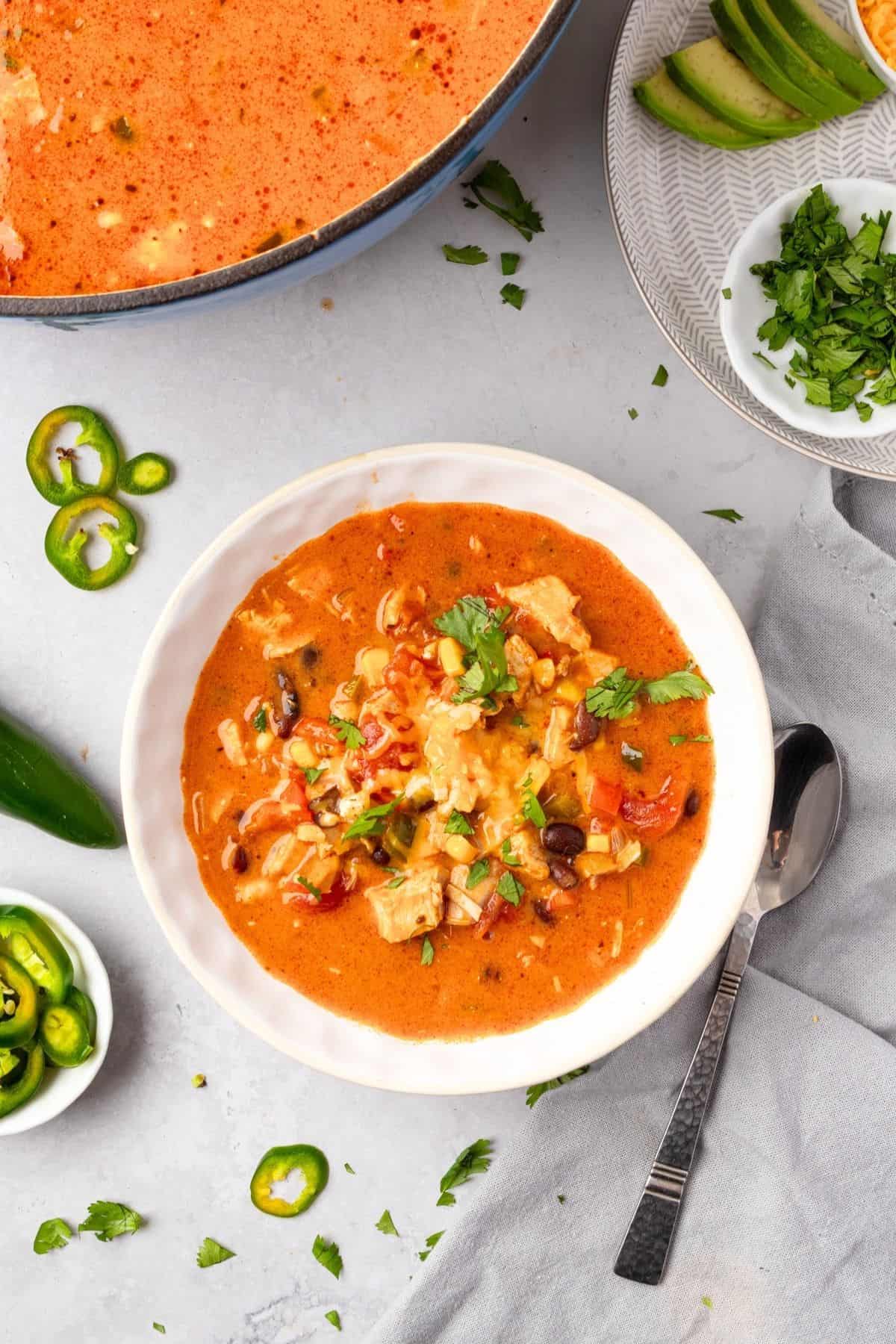 A white bowl of cheesy chicken enchilada soup.