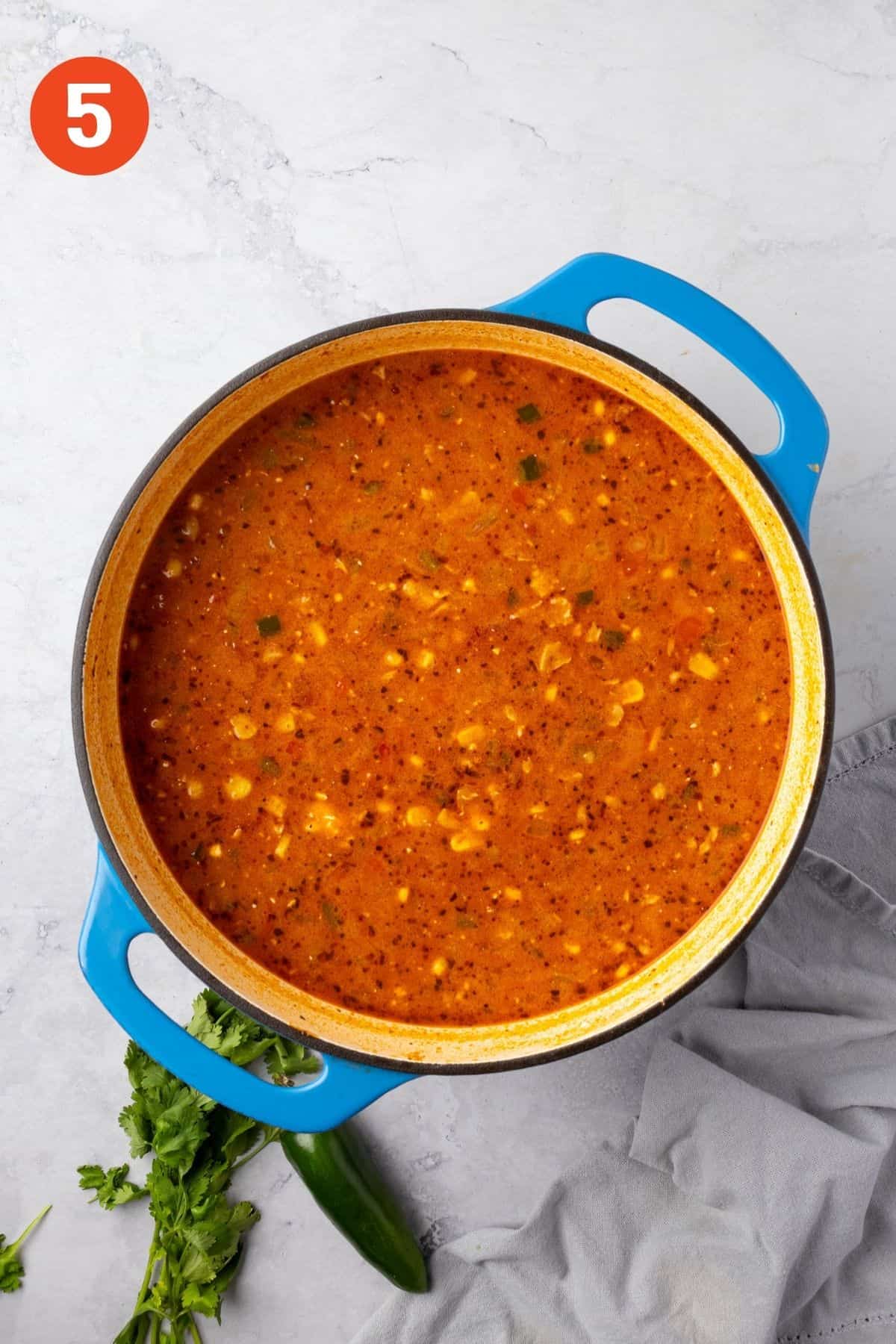 Soup with vegetables in a blue pot.