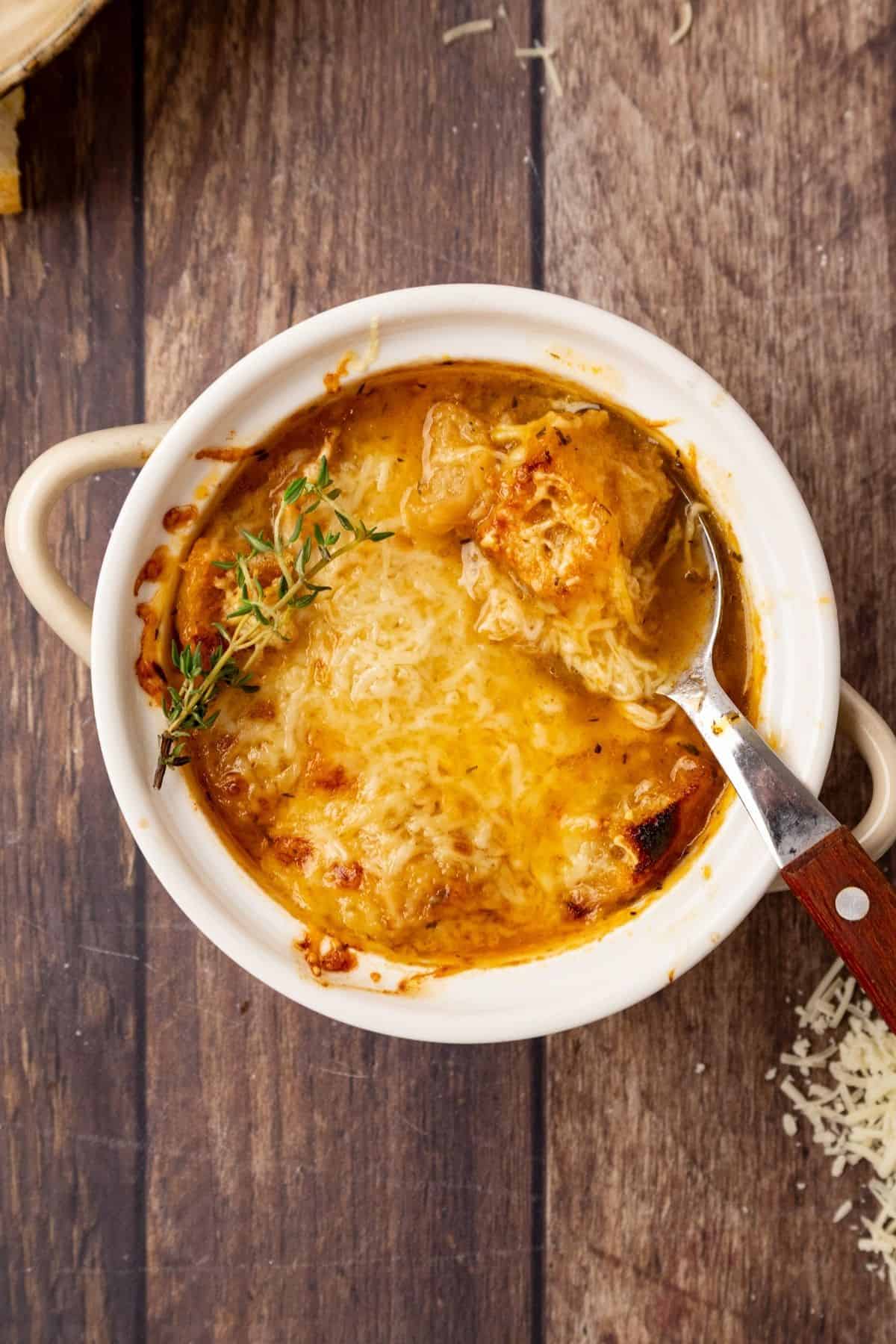 A bowl of Panera French onion soup with a spoon in the bowl. 