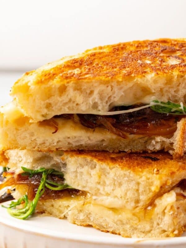 Sliced French onion grilled cheese stacked on a plate.